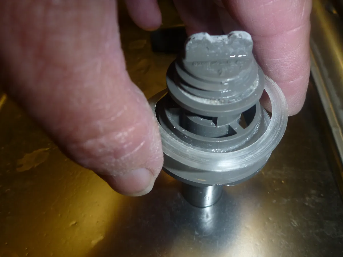 The interior base of a dishwasher partly disassembled, showing the sump and filter area
