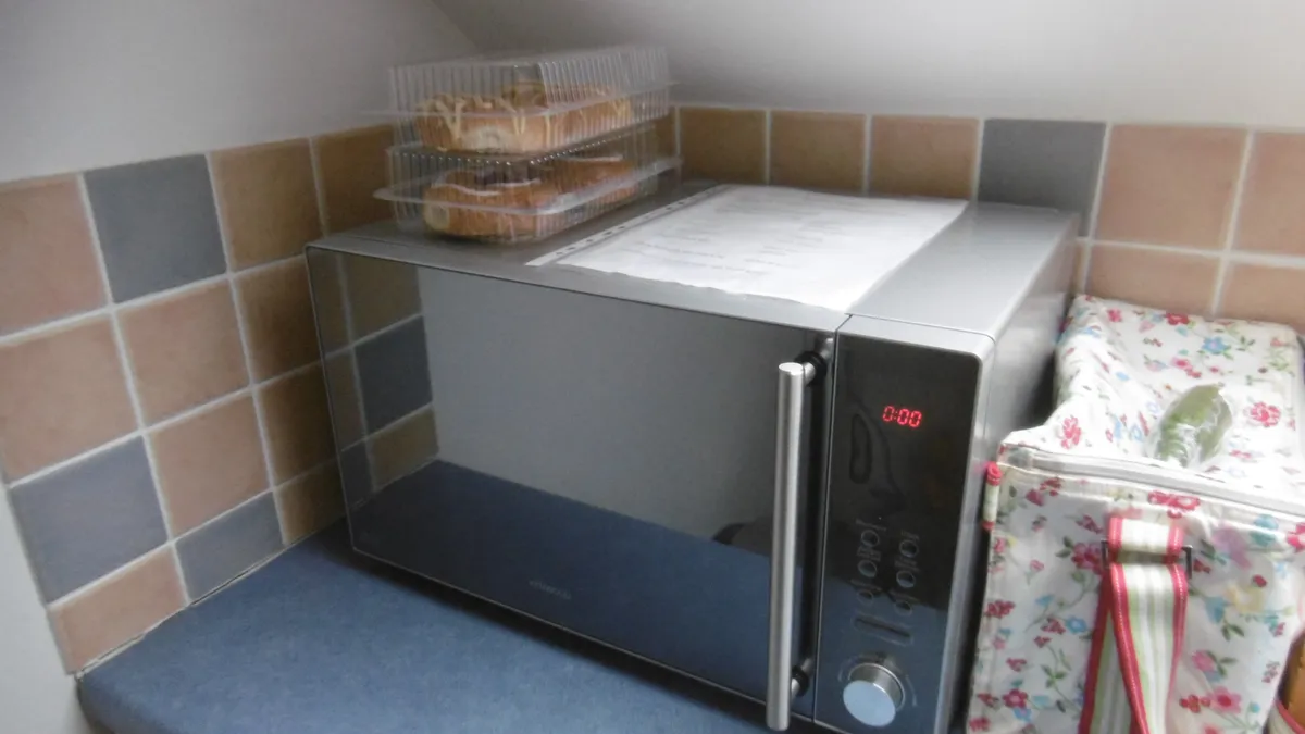 A microwave oven on a kitchen counter beside cupboards