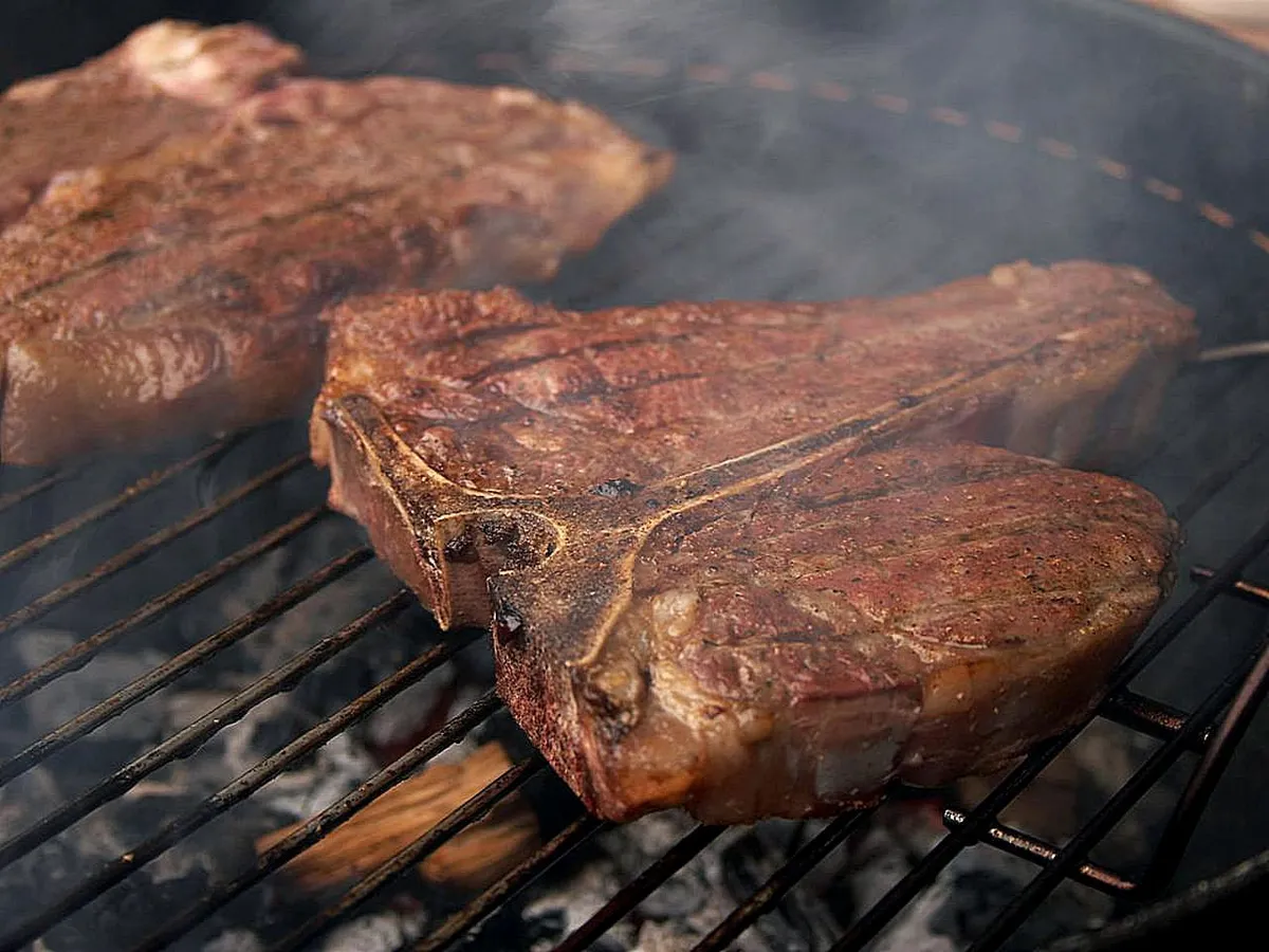 Porterhouse steaks searing over a hot grill