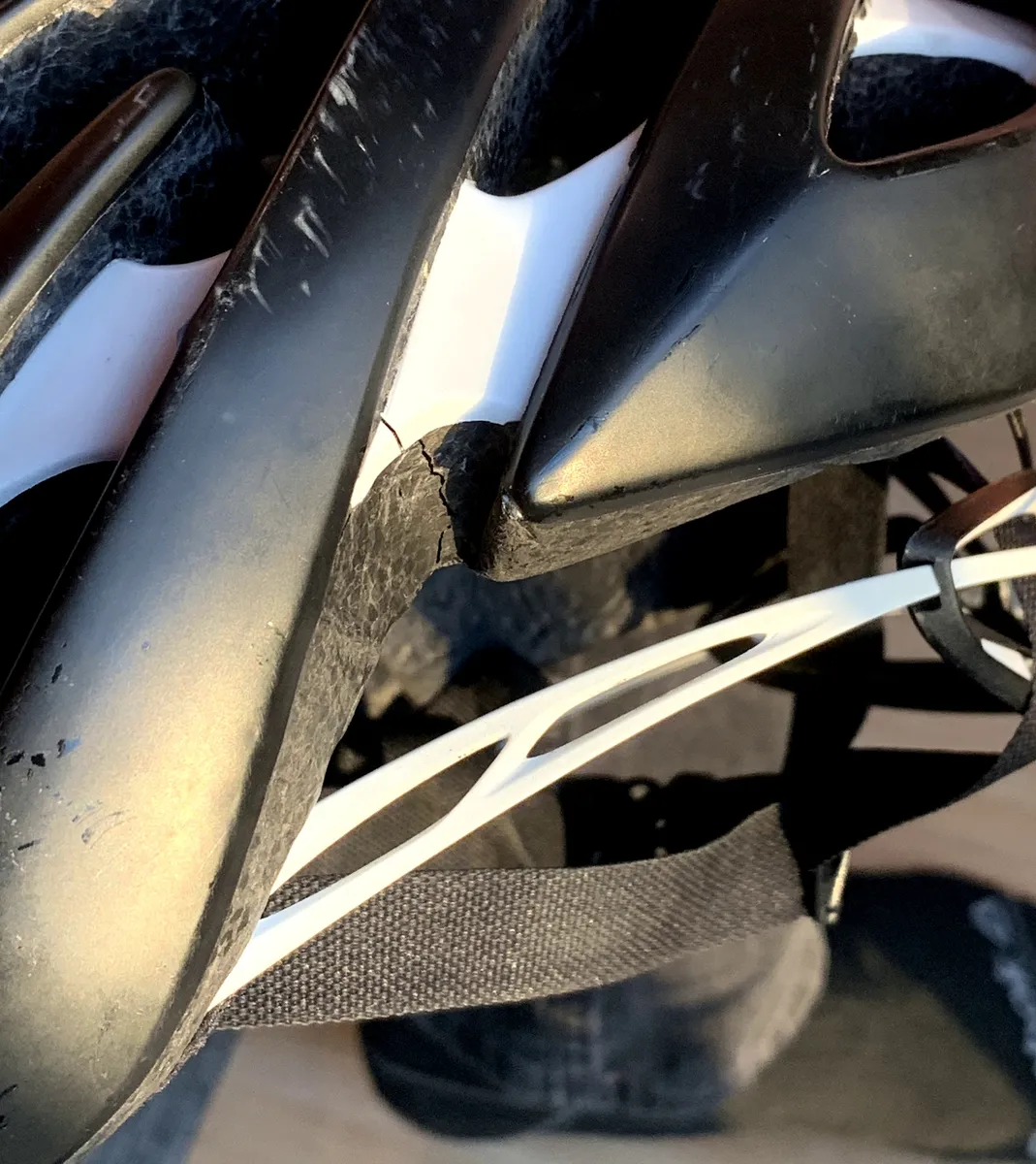 A bicycle helmet with a visible crack through the shell and foam