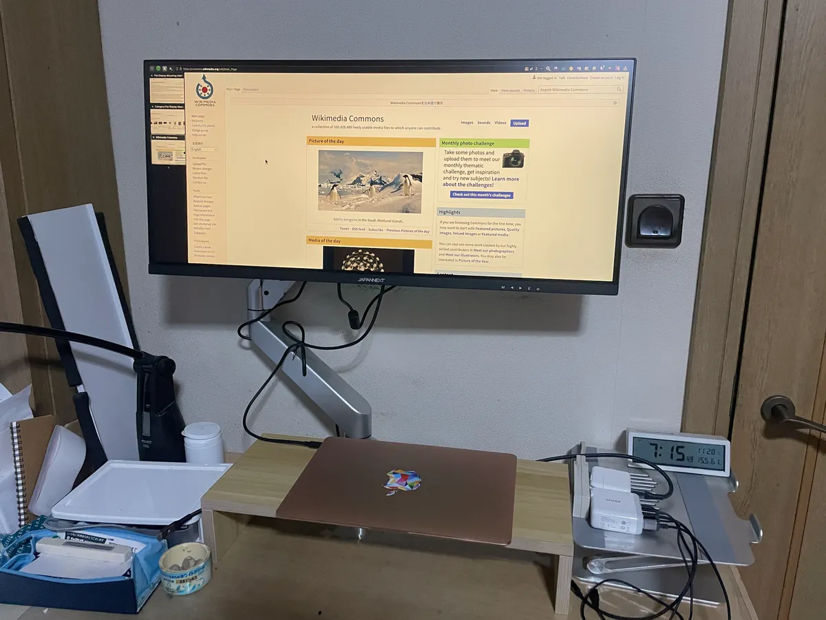 An ultrawide monitor mounted on an articulating VESA arm above a desk
