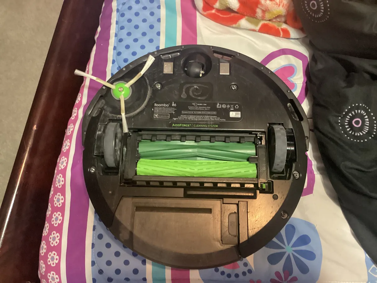 Underside of a robot vacuum showing brush roller and wheel design