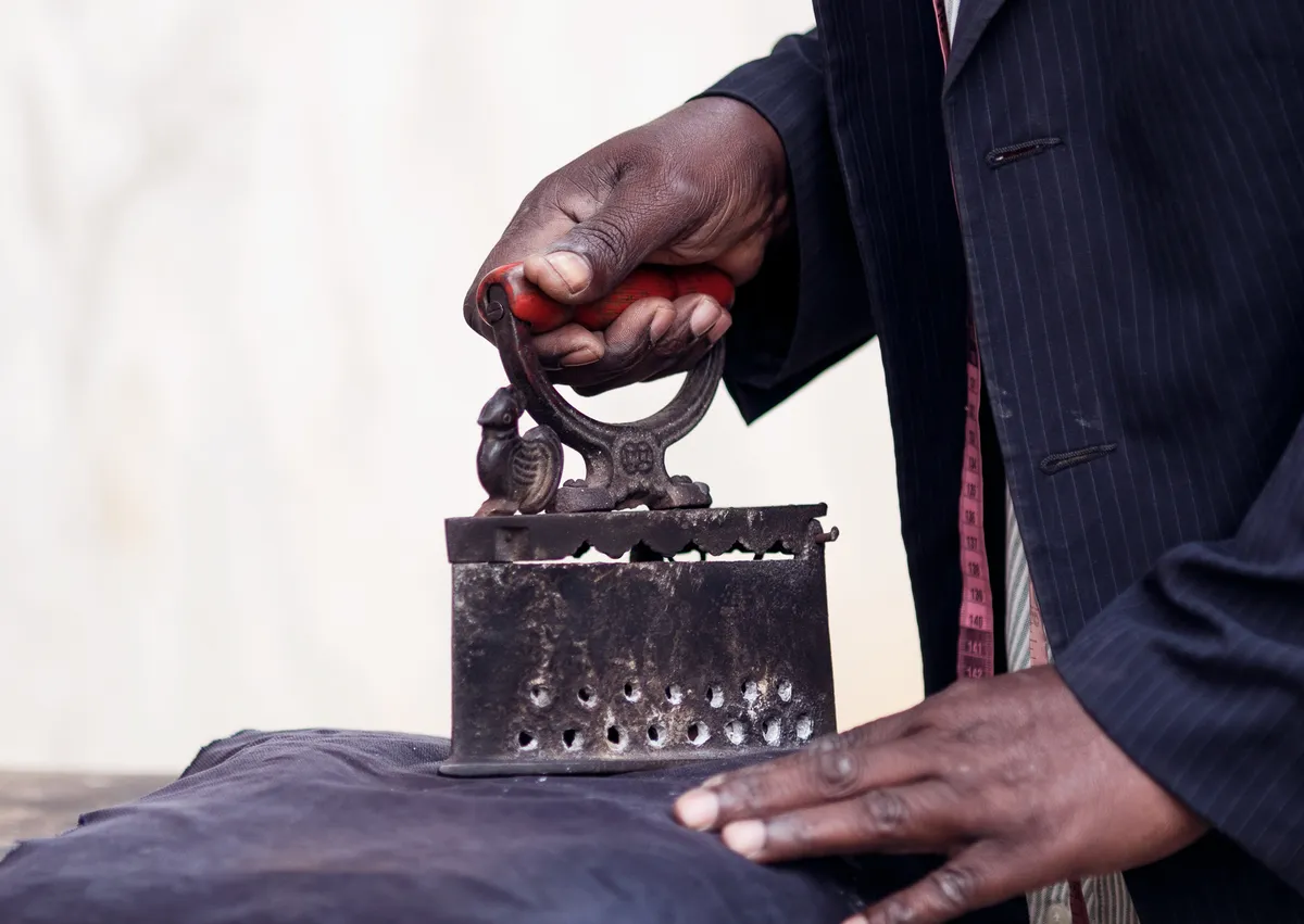 A tailor pressing fabric with an iron