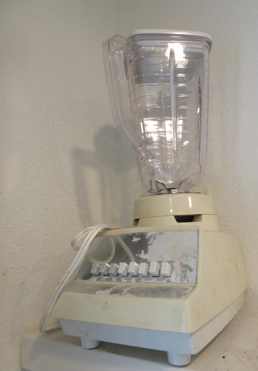 An older blender sitting on a kitchen shelf