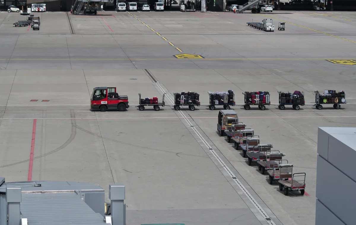 Luggage carts and baggage handling equipment on the tarmac at an airport