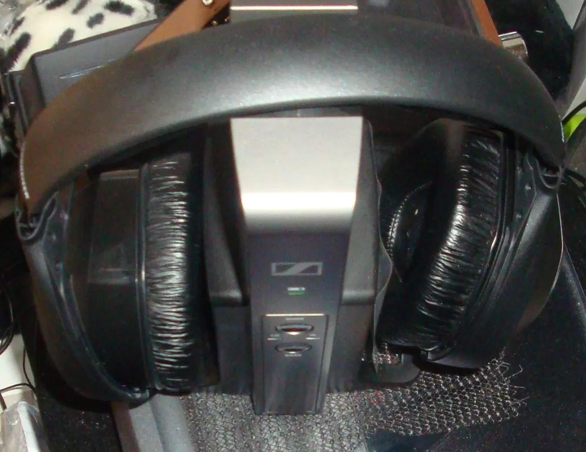 Wireless headphones resting on their charging and transmitter base station