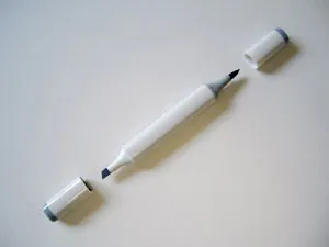 A single Copic dual-tip alcohol marker with one cap removed, showing the fine brush nib