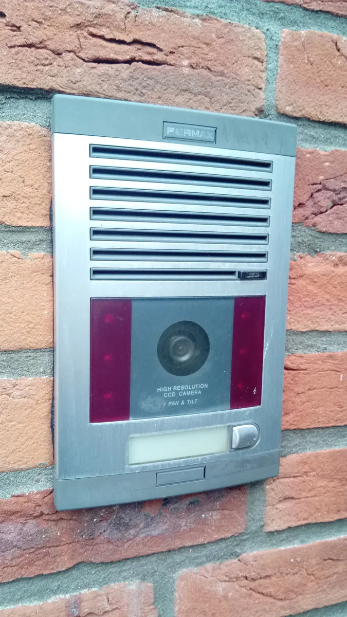 A hardwired intercom-style doorbell with integrated camera mounted at a building entrance