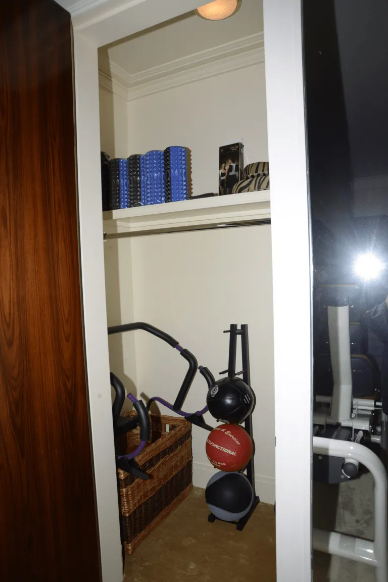 A home gym storage area with foam rollers, exercise balls and resistance bands