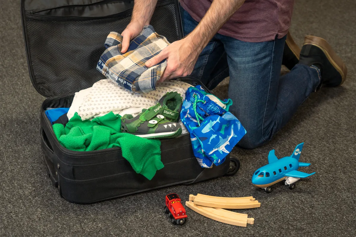 An adult packing a child's suitcase