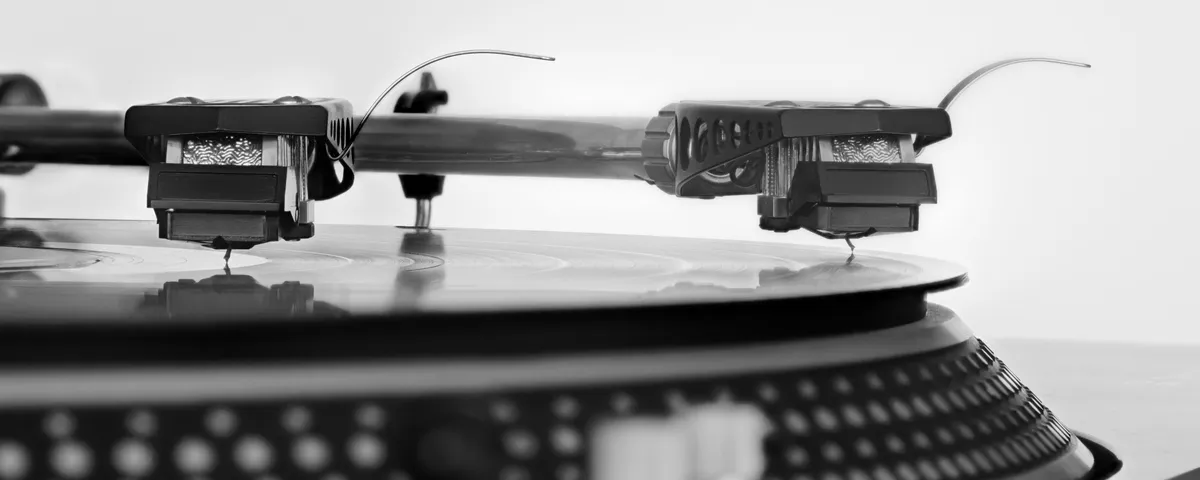 Close-up macro photograph of a turntable stylus tracking a vinyl record groove