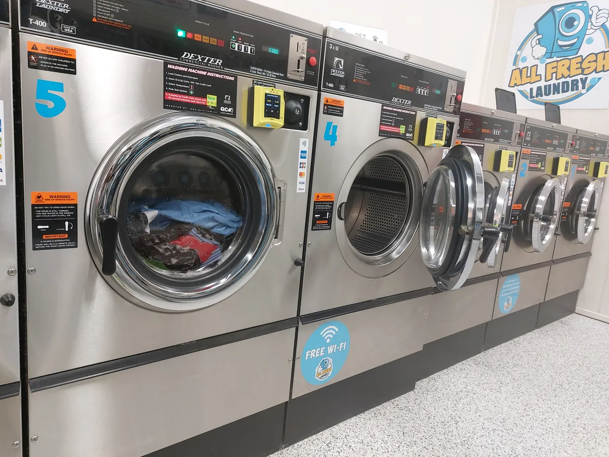 A row of commercial washing machines in a laundrette