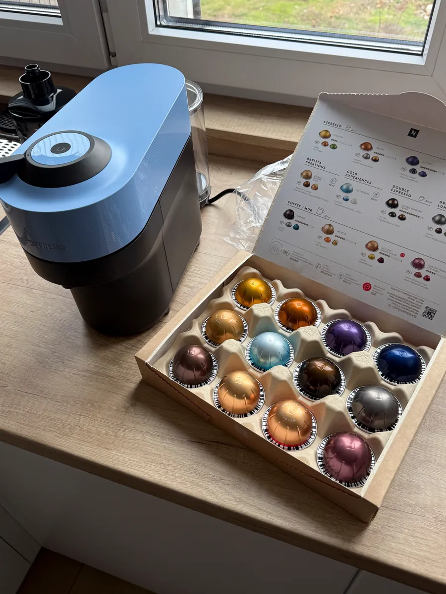 A capsule coffee machine on a kitchen counter surrounded by coffee capsules