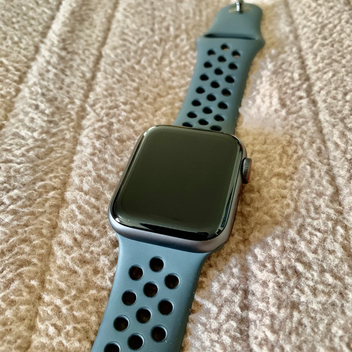 A smartwatch with a perforated sport band on a wrist