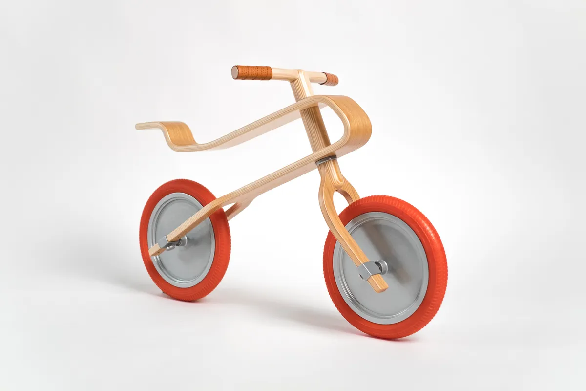 Wooden balance bike with an oak frame and red tyres