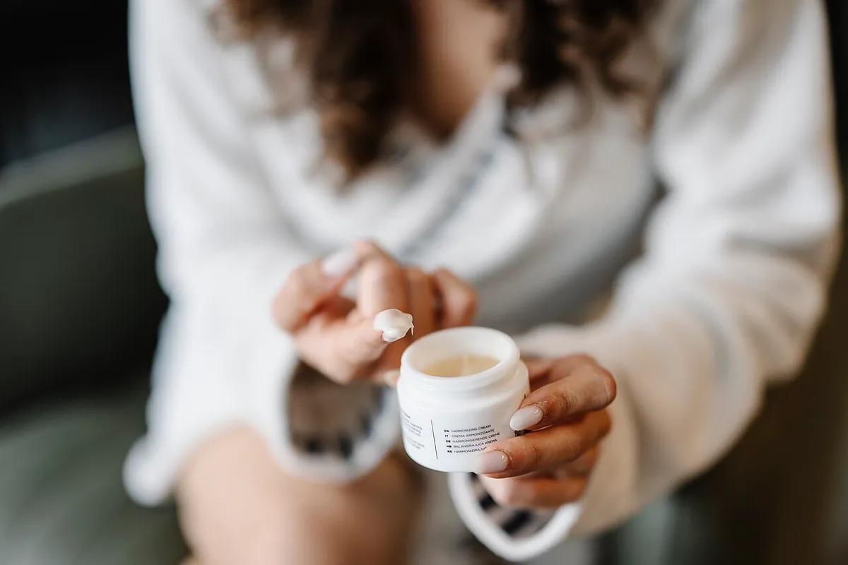 Close-up of applying moisturizing cream from a jar