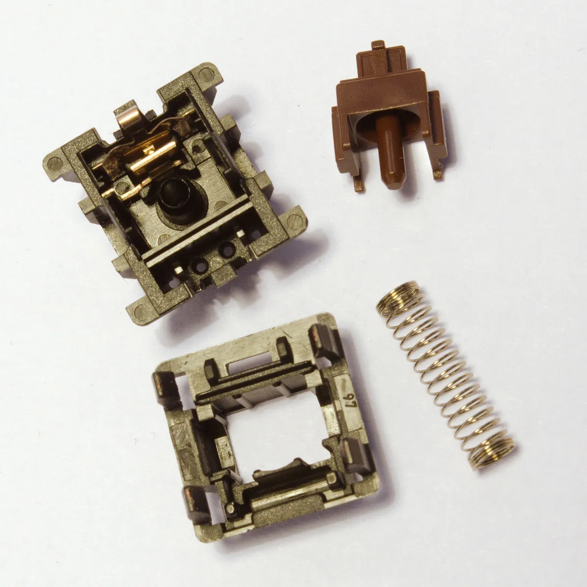 Disassembled mechanical keyboard switch showing stem, spring and housing