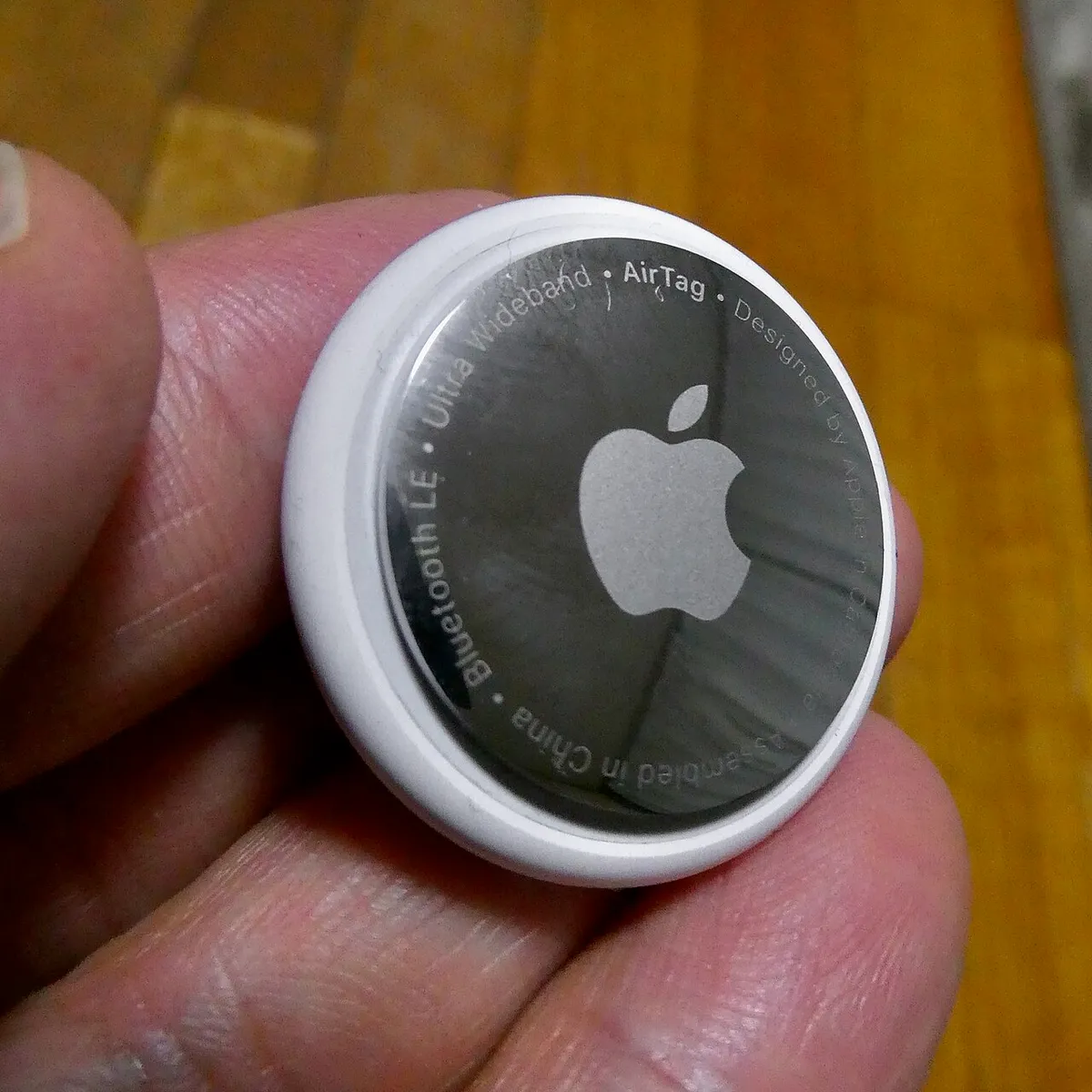 Apple AirTag shown next to a travel bag for size comparison