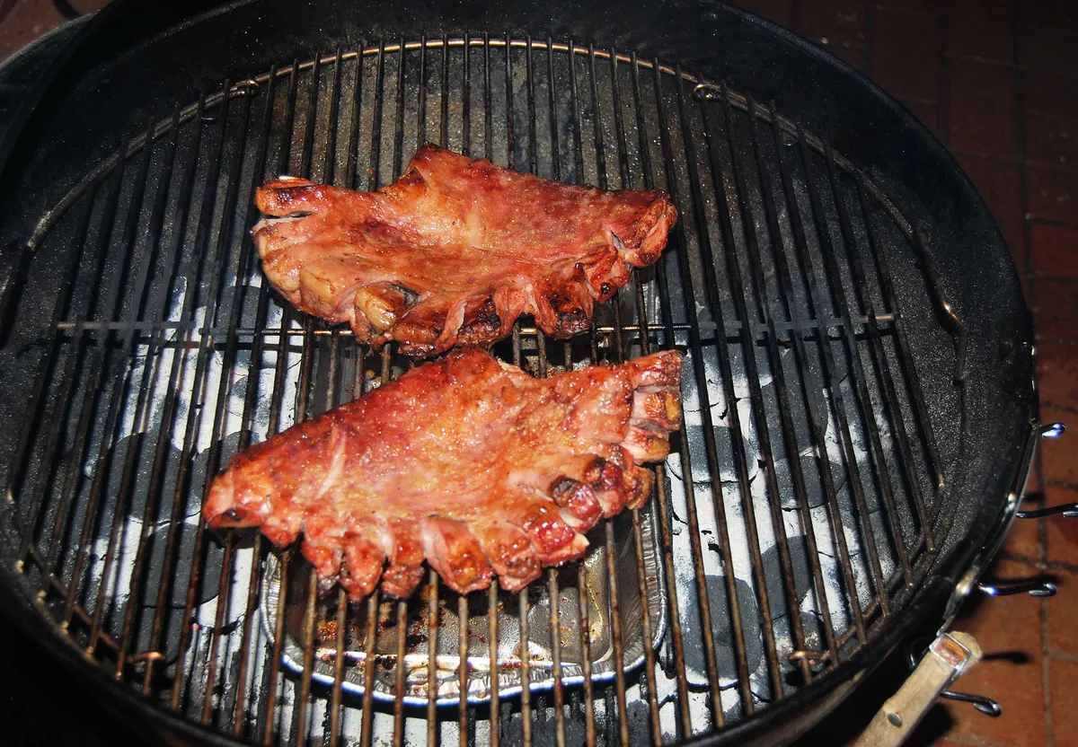 Pork ribs cooking on a Weber kettle over indirect heat