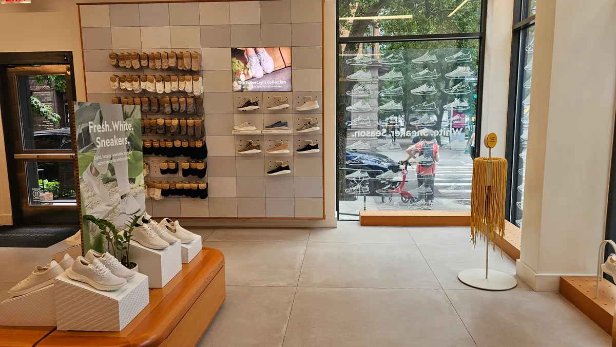 Interior of an Allbirds retail store displaying shoes on wooden shelving