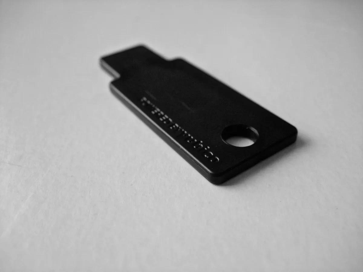 Black YubiKey security key held between two fingers showing its compact size