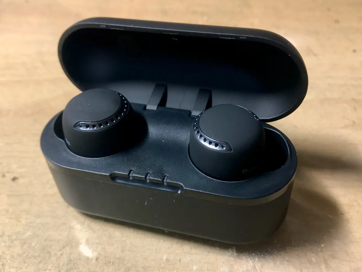 Close-up of a person's ear with a true wireless in-ear earbud fitted, illustrating typical in-ear fit and stem design