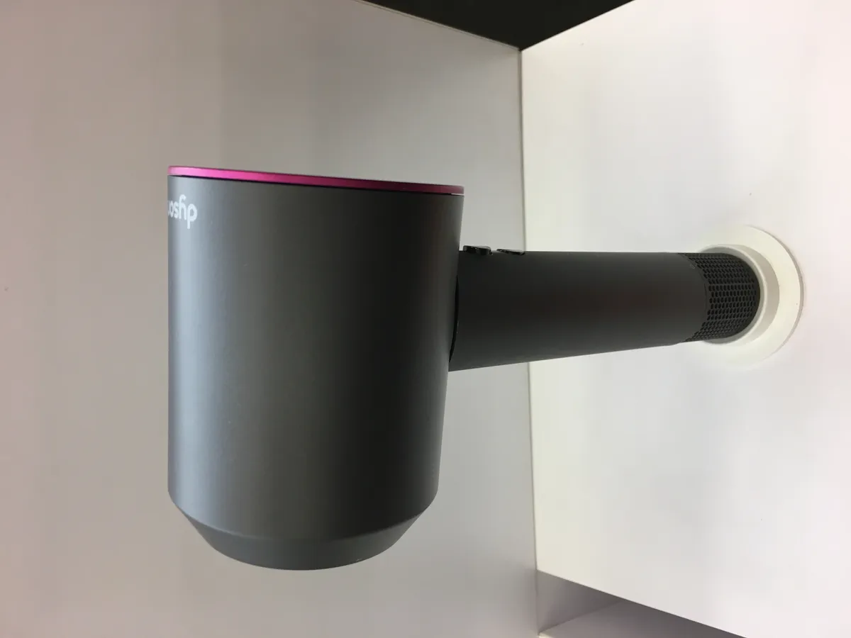 Close-up of a Dyson hair styling tool head showing the compact motor housing typical of the brand's styling range