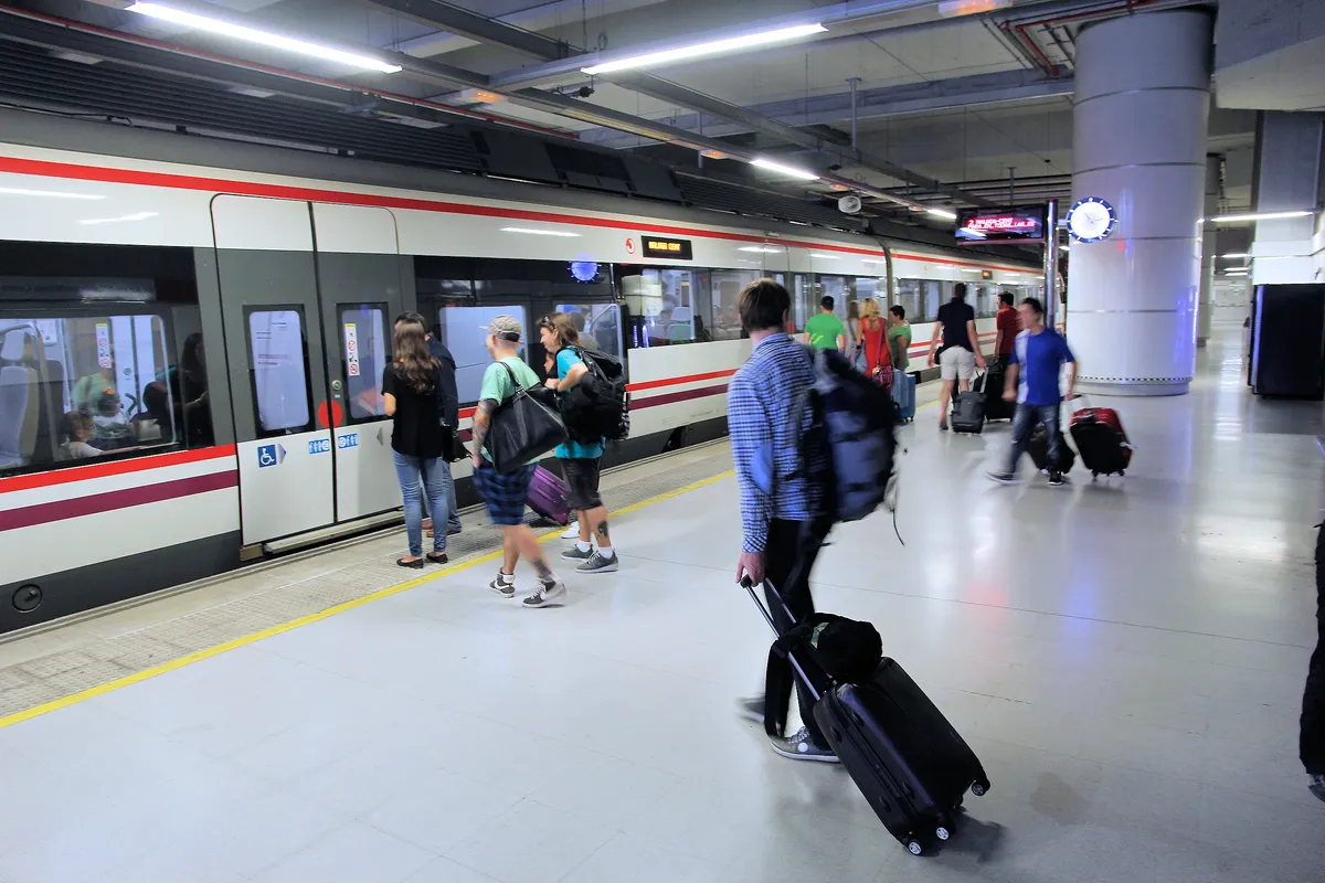 Travelers wheeling hardshell suitcases through an airport train station, the everyday setting where carry-on durability is tested