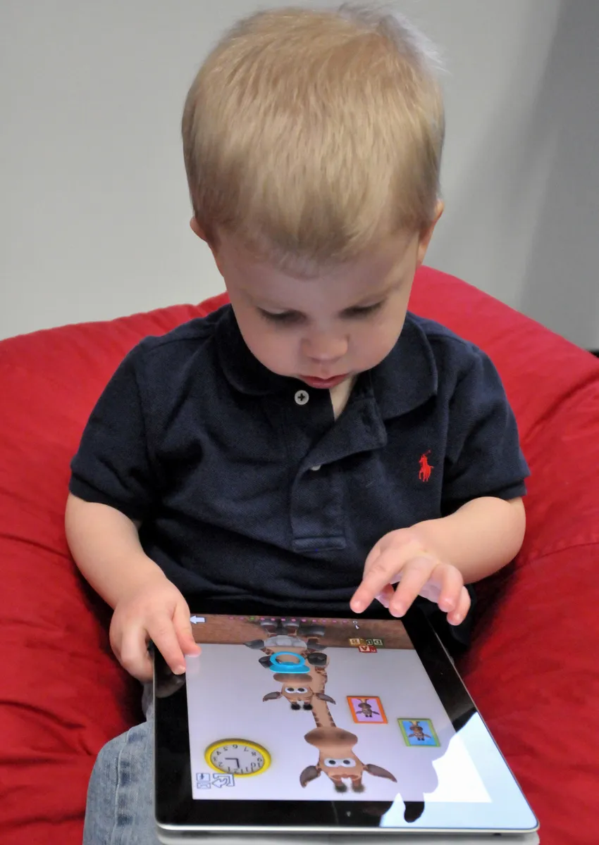 Child holding and using an Apple iPad tablet