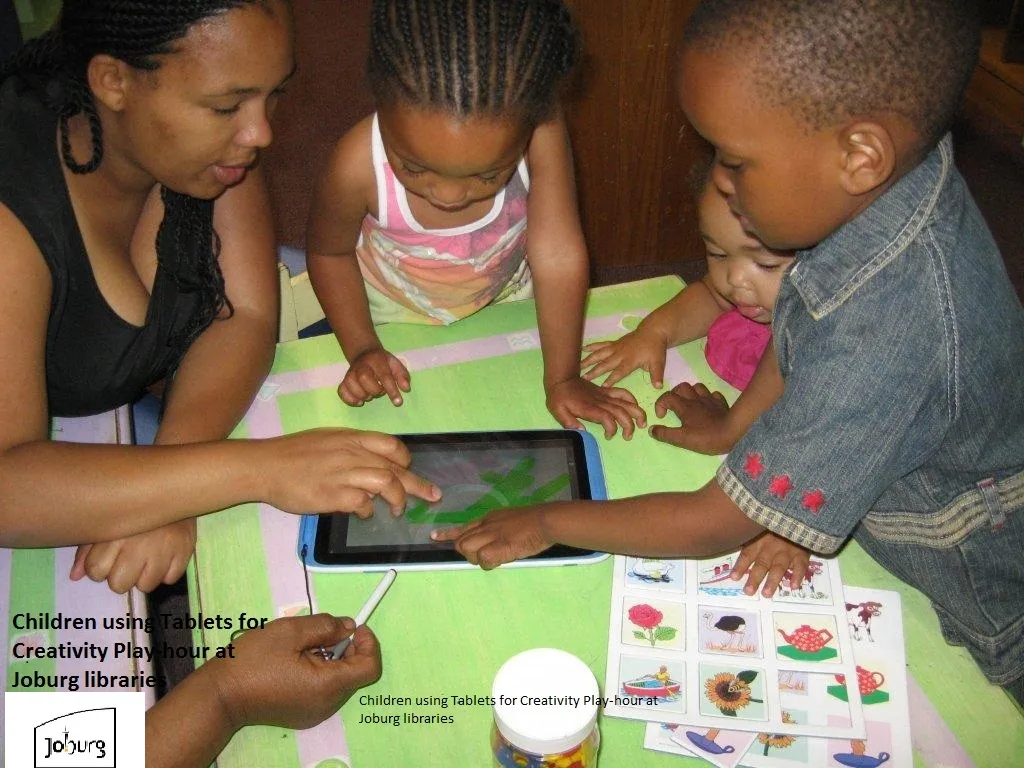 Children using tablets together with a parent at a library table