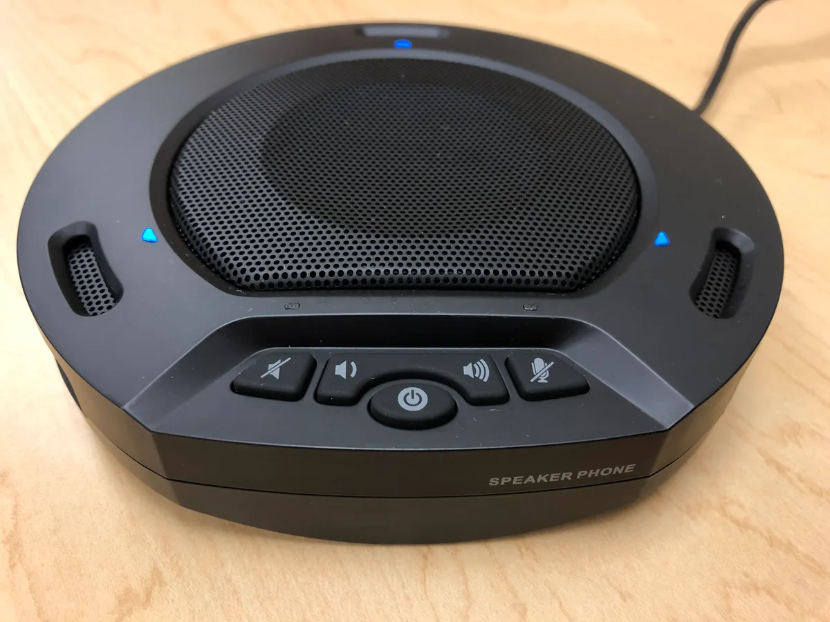 A conference room USB speakerphone device on a table, representative of the speakerphone category
