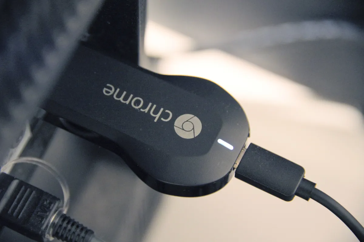 A Chromecast device plugged into the HDMI port on the back of a television