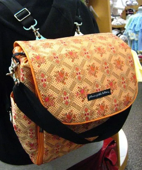 Person wearing a structured backpack-style diaper bag while out with a stroller
