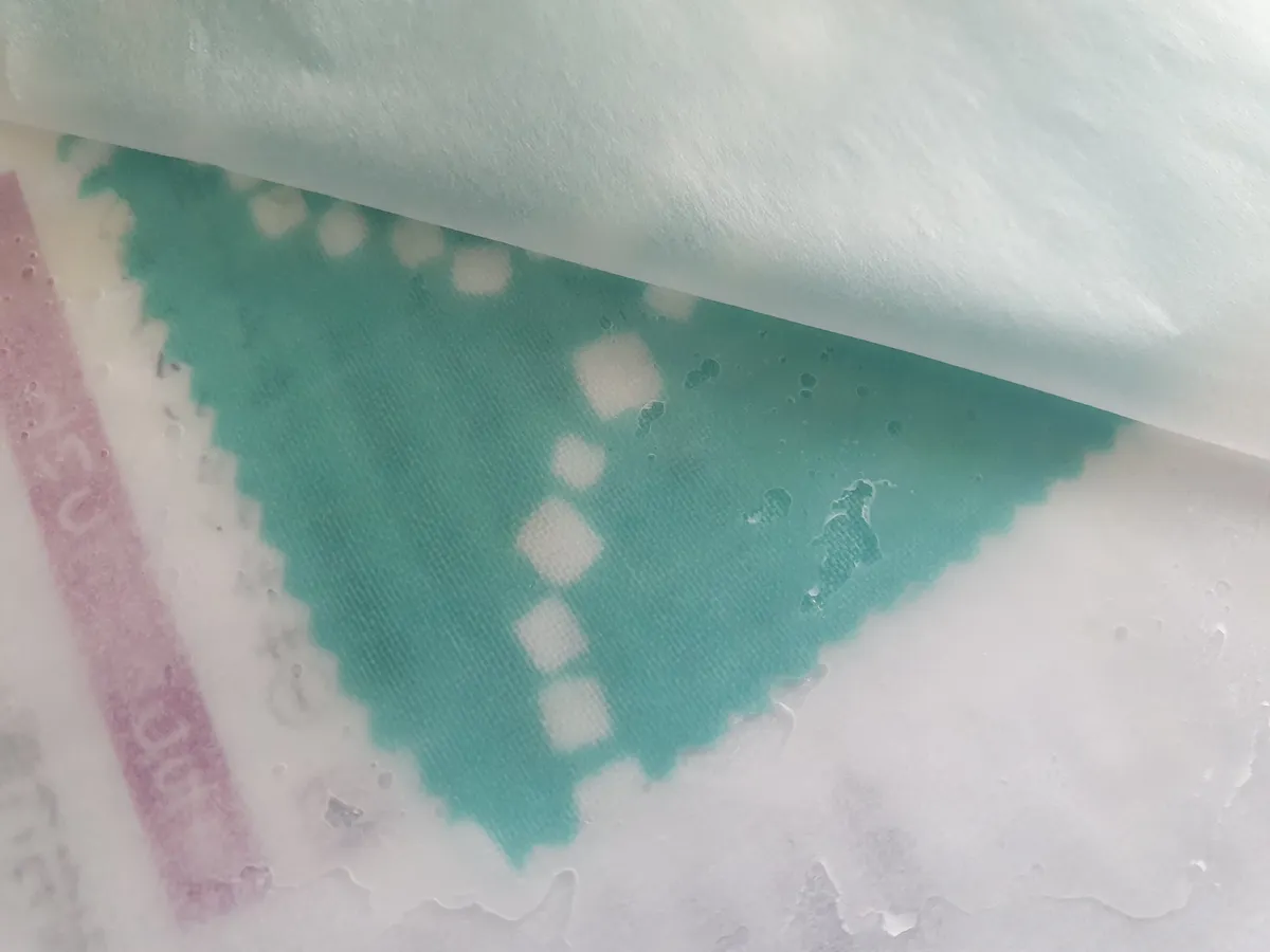 Cotton fabric being coated with melted beeswax during the wrap manufacturing process