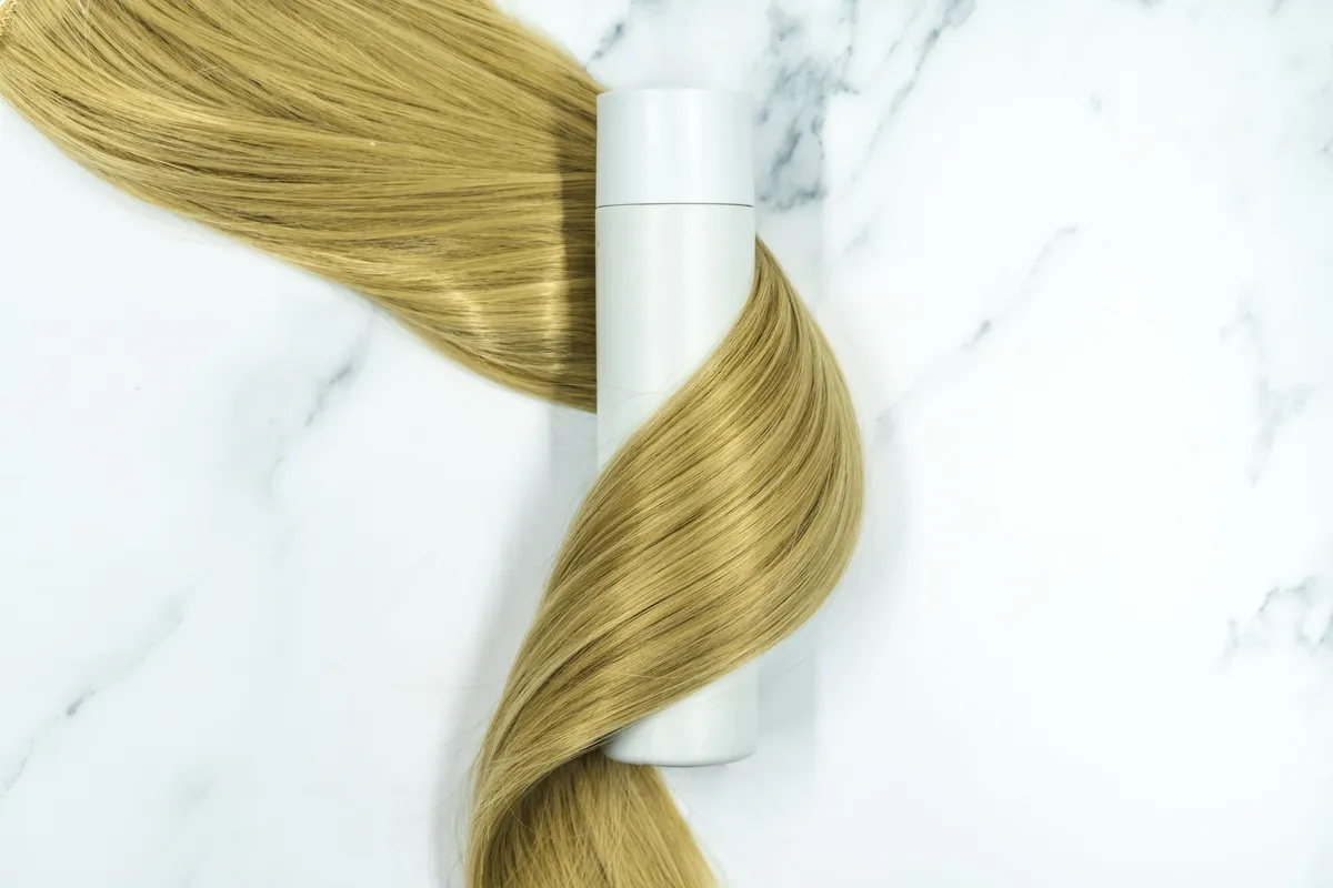 Long hair being handled alongside hair care products
