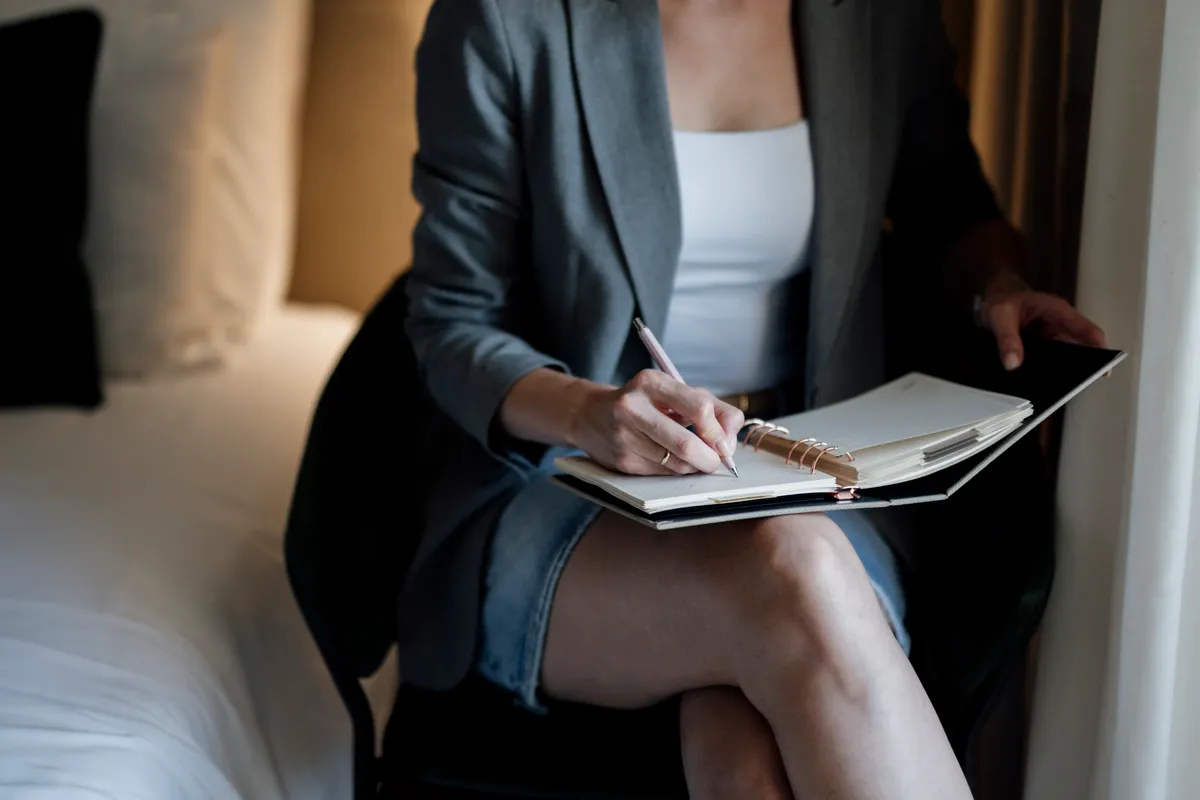 Woman writing in a notebook while seated, reflecting casual daily journaling use