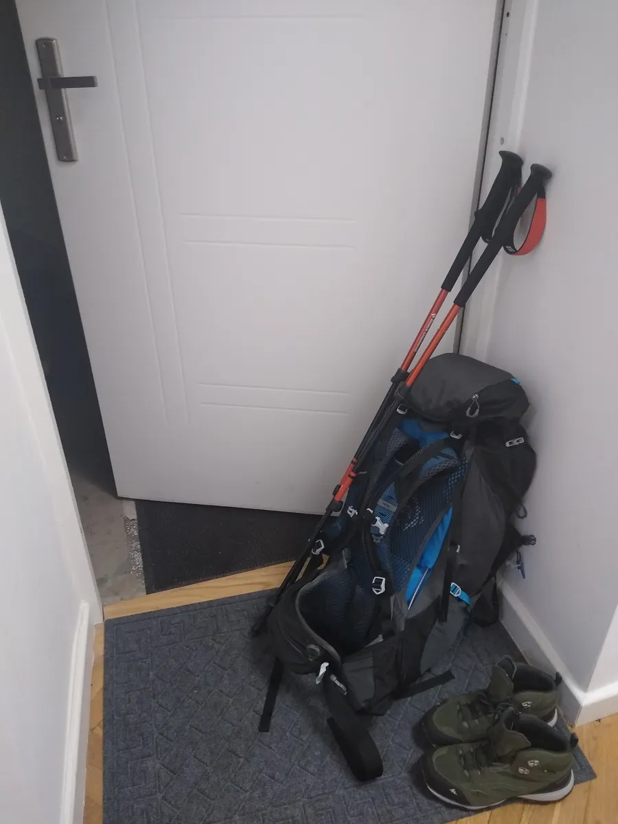 A backpack packed for a hike, shown alongside trekking poles and hiking shoes