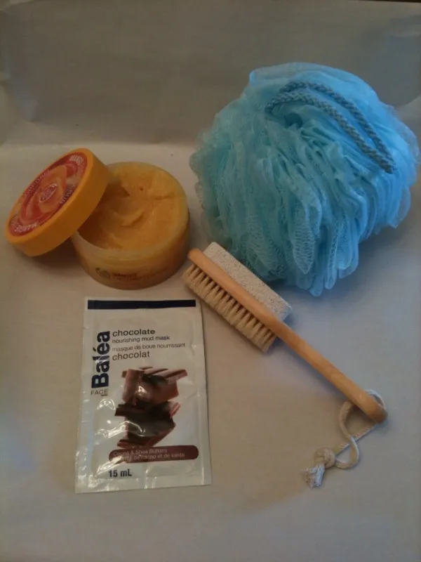 A collection of manual exfoliation tools including a bristle brush, pumice stone, and body scrub, for comparison against sonic silicone devices