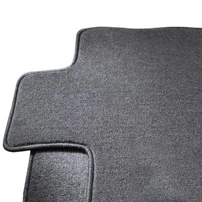 Tailored car mats sized precisely to a vehicle's footwell contours, sitting on a workshop floor before installation