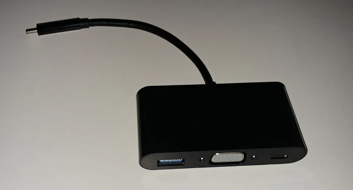 A small USB-C hub adapter with multiple ports on a light background