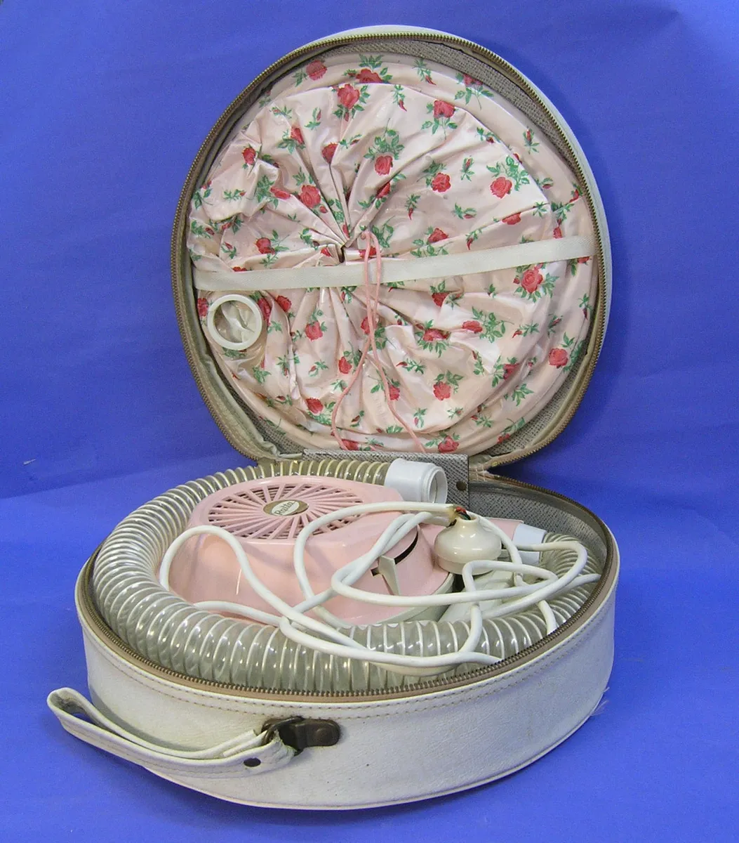 A vintage handheld hair dryer unit shown from the side, illustrating typical hair dryer construction with a barrel, handle, and vents