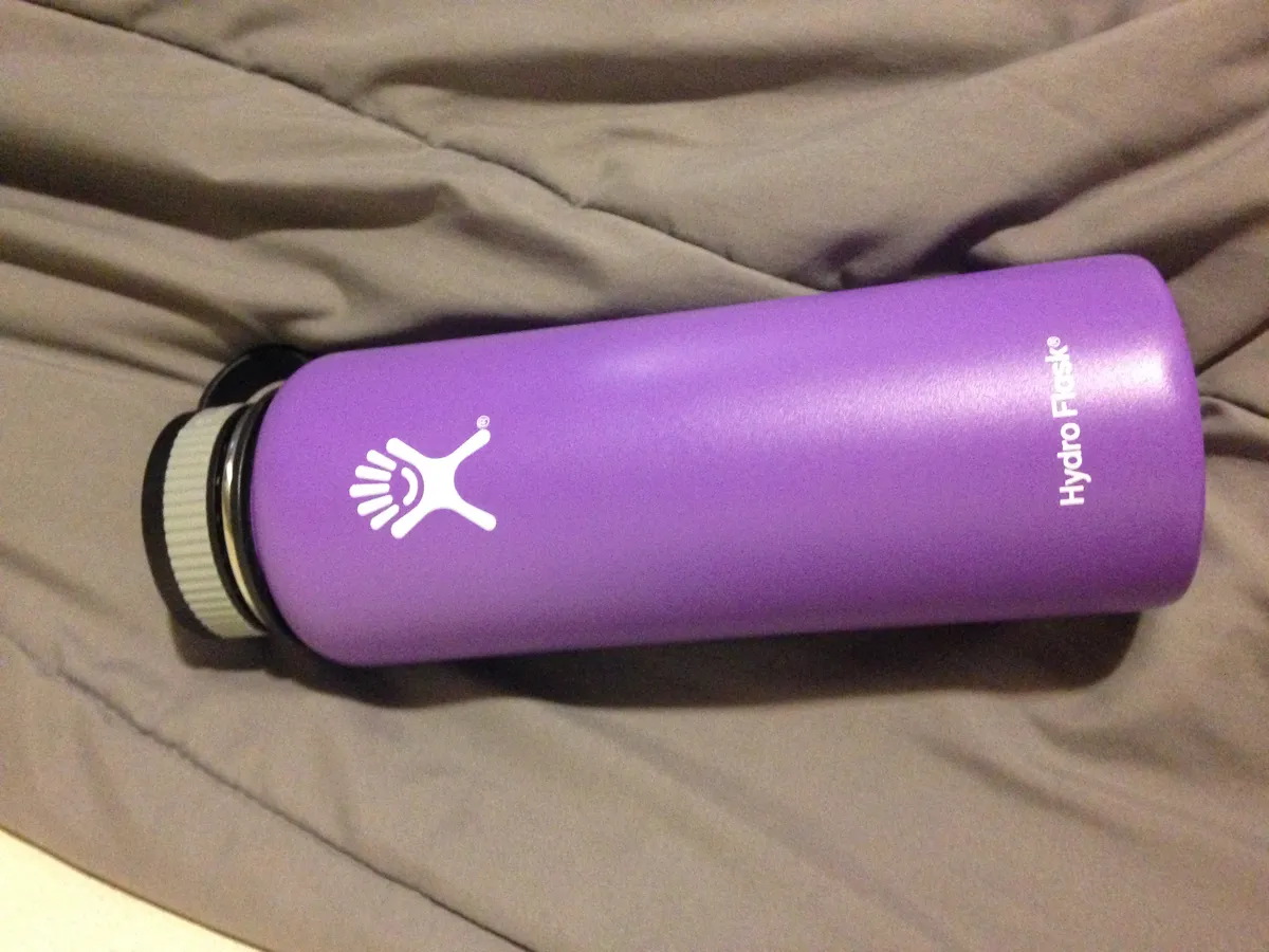 Purple Hydro Flask bottle held in one hand outdoors