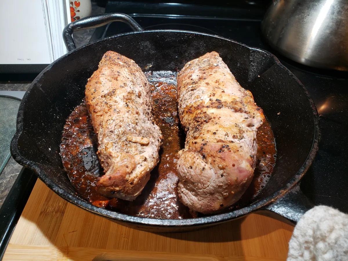 Seared and roasted pork tenderloin resting in a cast iron skillet