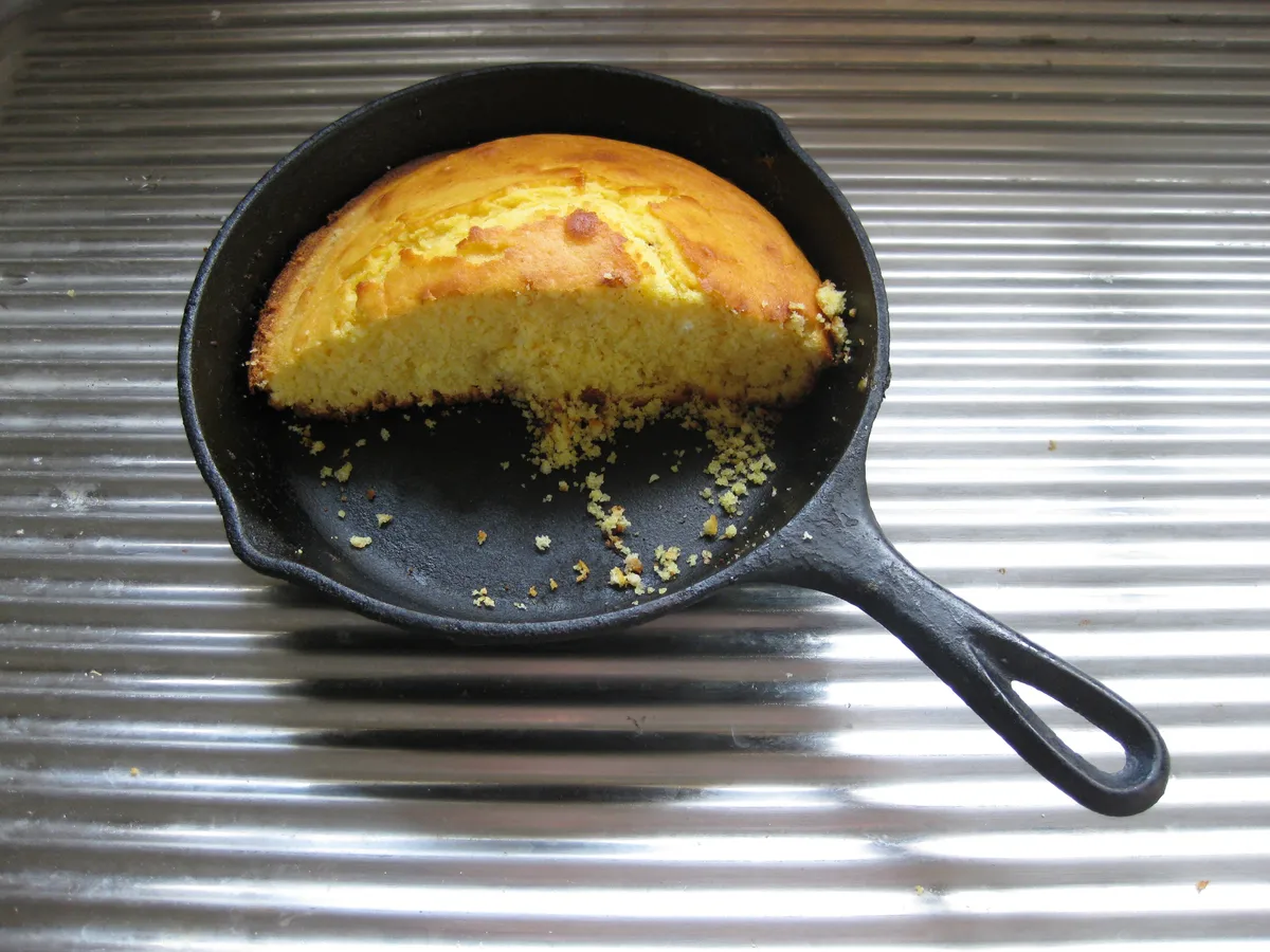 Golden baked cornbread cooling in a round cast iron pan