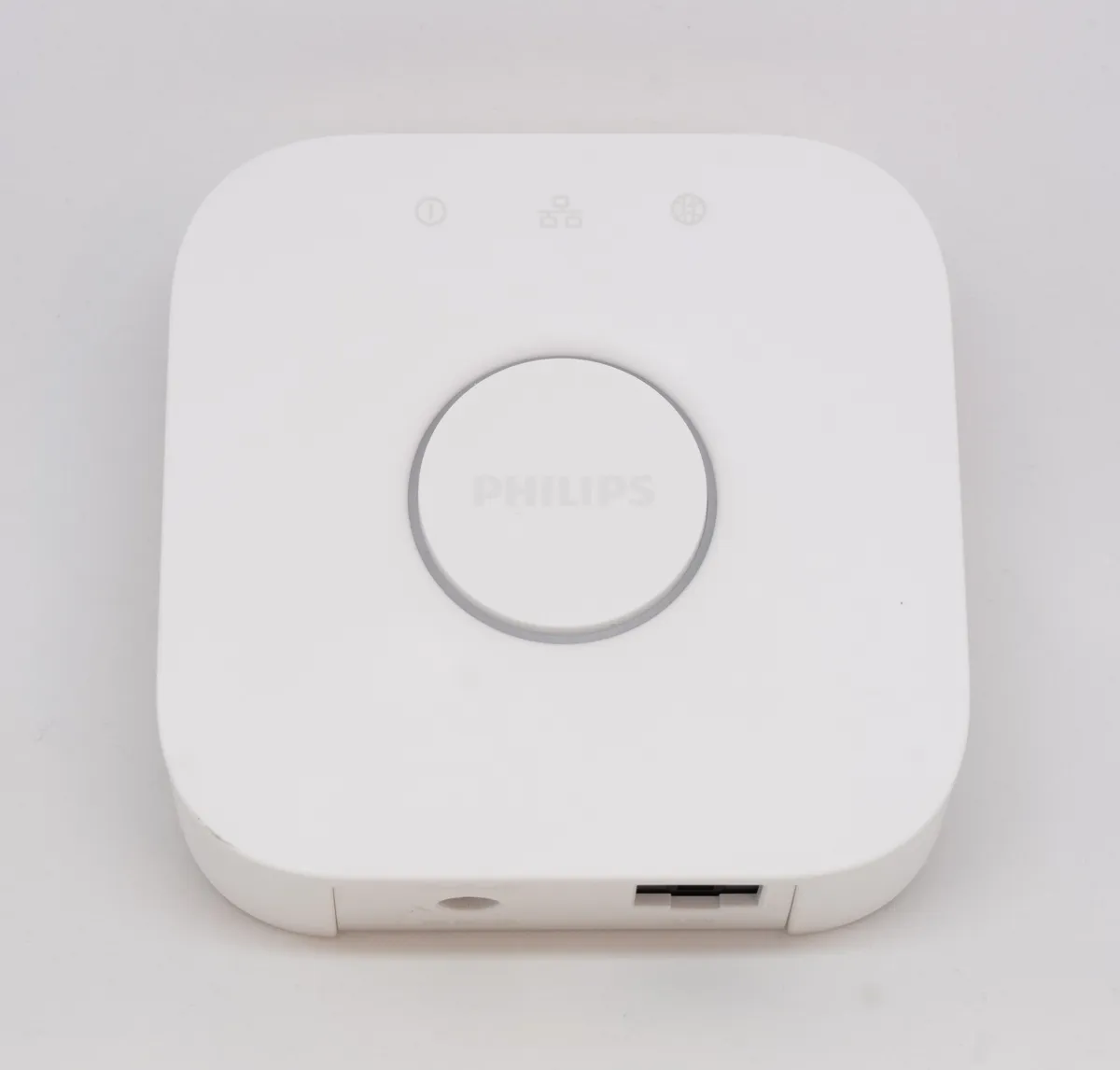 Philips Hue Bridge hub connected and sitting beside a router