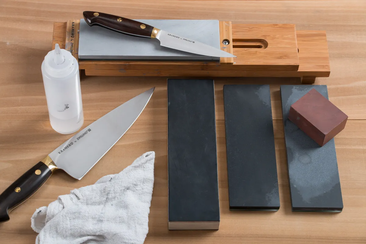 A whetstone and knife sharpening tools laid out on a bench