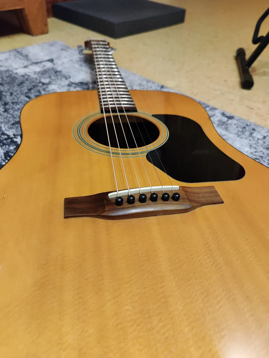 The body and soundhole of a laminate-back dreadnought acoustic guitar