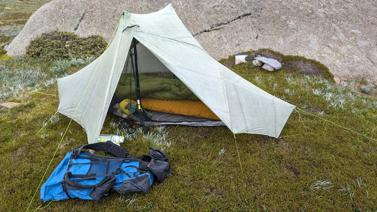 A tent packed alongside a sleeping bag and backpack for a walk-in trip