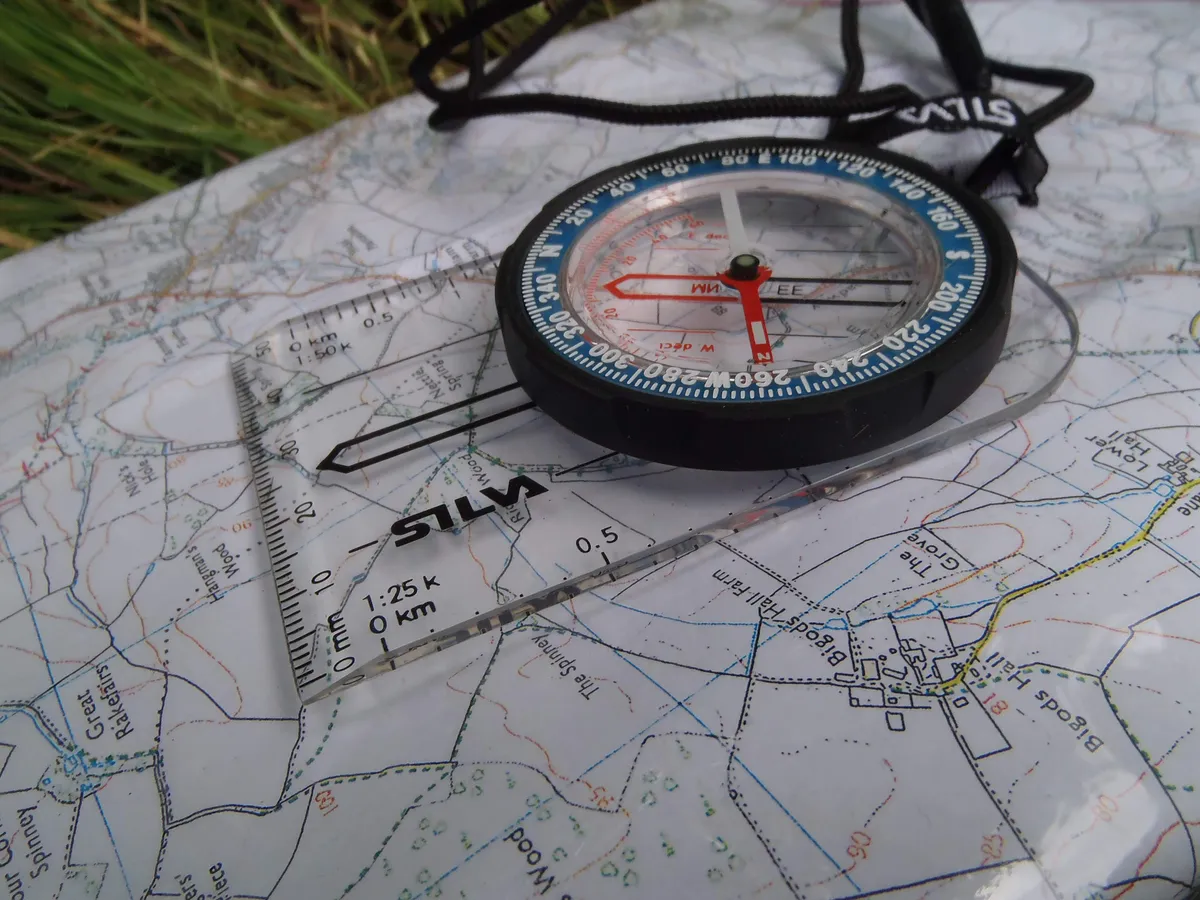 A baseplate compass resting on a topographic map