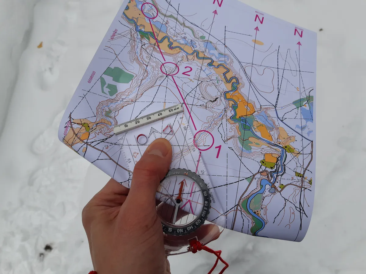 A baseplate compass being used on an oriented map to take a bearing